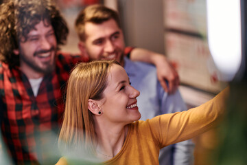 A diverse group of business professionals take a break from their tasks in a modern startup office to capture a creative selfie, showcasing teamwork and a vibrant workplace culture