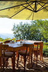 Cutlery and wine glasses on wooden table in an open-air restaurant overlooking the mountains