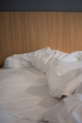 White crumpled pillows on hotel bed after use, relaxing holiday concept