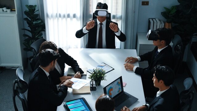 Top view of manager working on laptop and sending data analysis to business people by using VR glass headset while diverse team planning marketing strategy and looking at financial graph. Directorate.