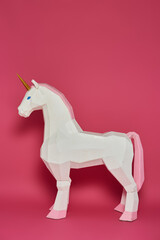 A white unicorn with pink accents stands against a pink background.