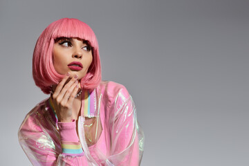 A woman with pink hair and a transparent, vibrant jacket looks to her right.