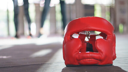 Obraz premium Boxing Headquard and leather mitt glove placed on canvas of ring in camp of training boxer. Equipments for protection during heavy sparring sessions, Used for Muay Thai, Kick Boxing and MMA Training