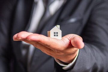 Businessman holding house model in hand, housing and property concept Real estate investment.