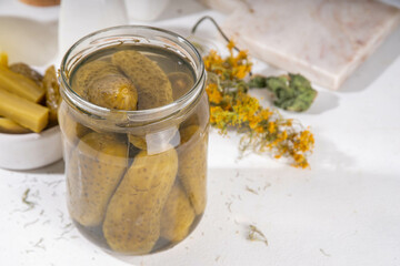 Homemade pickles in jar. Tasty gourmet pickled cucumbers with spices on kitchen table background...
