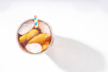 Trendy soda and pickles cocktail. Cola and pickled cucumber cold iced sweet sour soft drink in glass, on kitchen table with marinated cucumbers, copy space