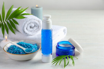 Spa composition. Cosmetic products, towels, sea salt and burning candles on light table