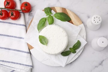 Fresh ricotta (cream cheese), basil, spices and tomatoes on light marble table, flat lay