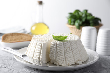 Tasty ricotta (cream cheese) and knife on grey textured table, closeup