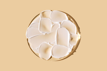 A smear of white cream on a beige background on a round stand.