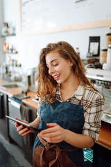 Young woman owner with tablet stands behind the counter of a coffee shop. Business concept. Takeaway food.