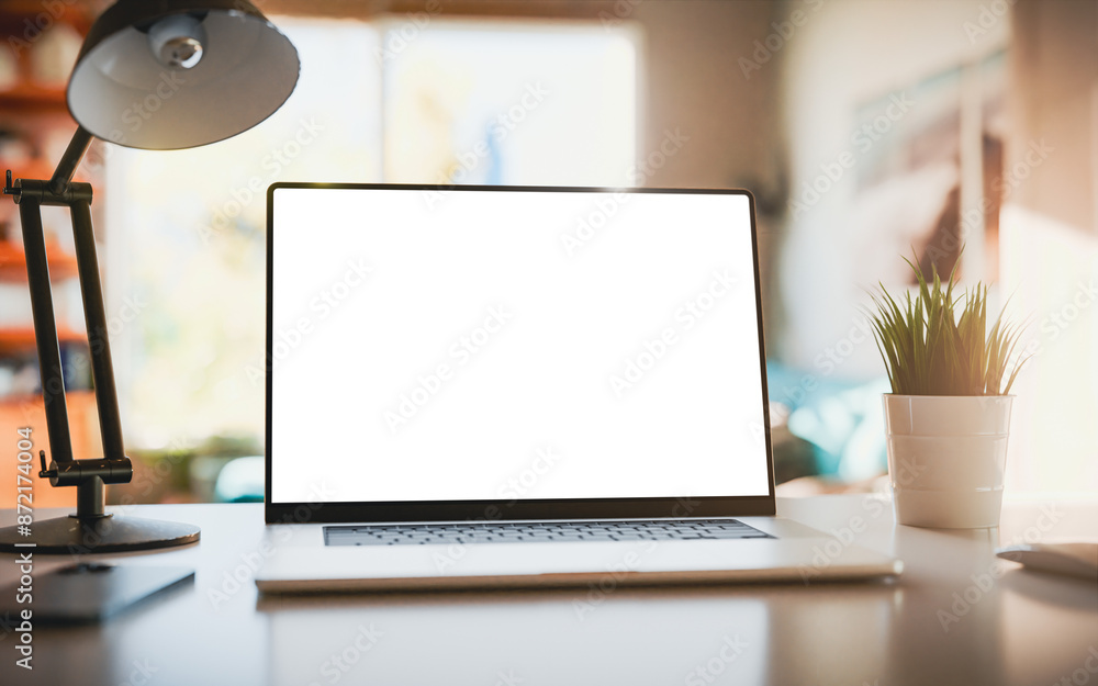 Poster laptop with a blank screen on a table in a bright home office. perfect for inserting your own conten