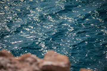 Close up of the blue waves and the rocks of the cliff