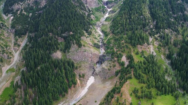 Aerial view of a small river in the middle of a green field and forest in the wilderness. Natural Resource and Ecosystem. Taip Meadows, Swat Valley, Pakistan.