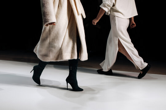 Cropped figures of fashion models women wearing white outfits. Stylish cloth. Two fashion models walking the runway on Fashion week