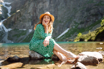 Woman tourist in summer dress enjoying beauty of nature looking at mountain lake. Concept of lifestyle, fashion, travel.