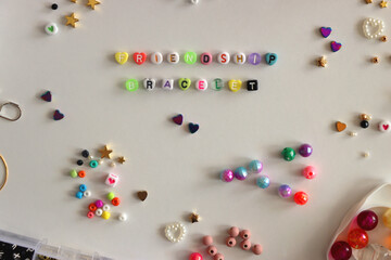Making friendship bracelets with letter beads. Jewelry making supplies on the table. Flat lay.