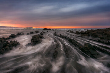 Sunset on Barrika beach, Bizkaia, with the waves entering with force among the flysch