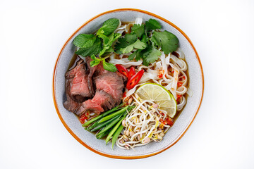 Pho Bo traditional Soup with beef, rice noodles, ginger, lime, chili pepper in bowl. Close up. Vietnamese and Asian cuisine.