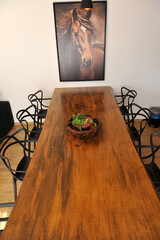 interior de mesa de jantar de madeira rustica com quadro de cavalo ao fundo 
