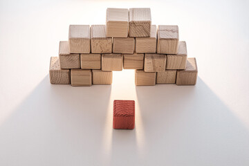 Obraz premium A single red wooden block stands out against a background of natural-colored wooden cubes arranged in an arch shape.