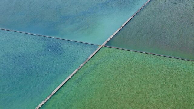 Aerial view of saltern evaporation ponds or saltworks evaporation fields under sun for extracting sea salt