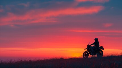 Fototapeta premium A serene moment as a motorcyclist pauses at dusk, bathed in the radiant hues of a vibrant sunset