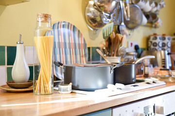 Cooking pasta in a home kitchen interior the pan has boiling water to cook spaghetti and raw ingredients on the kitchen counter
