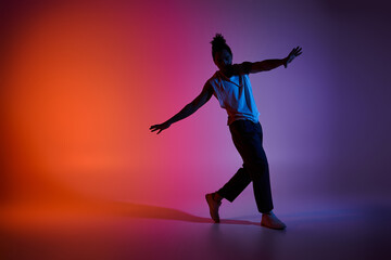 A young African American man dances with energy and grace against a vibrant gradient backdrop.