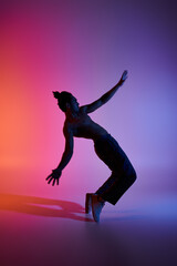 A silhouette of a young African American man dancing against a gradient pink and purple background.