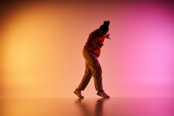 A young African American man dances against a colorful gradient background.