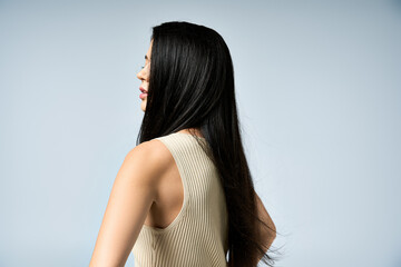 Fototapeta premium Black-haired woman in sleeveless top smiles over shoulder.
