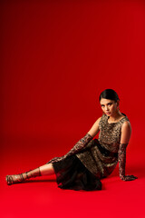 A young woman in a leopard print dress and matching gloves poses on a red background.