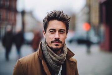 Naklejka premium Portrait of a handsome man with coat and scarf in the city