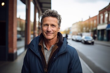 Fototapeta premium Handsome middle-aged man smiling at the camera in a city street.