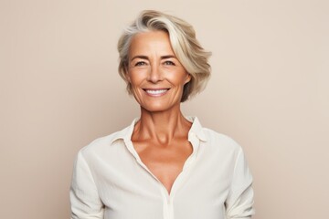 Fototapeta premium Portrait of a happy senior woman smiling at the camera against beige background