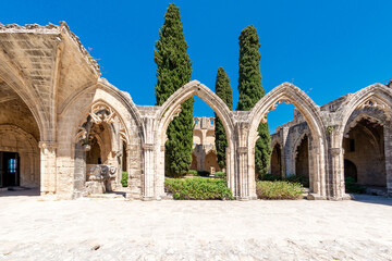 Bellapais Abbey ruins showing gothic architecture with stone arches and cypress trees. Cyprus