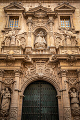 Vertical view of the baroque façade profusely decorated with columns and sculptures of saints of the church of La Merced, next to the university of Murcia, Spain