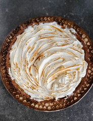 Appetizing beautiful lemon tart with meringue on a brown plate, on a stylish gray background. French baking.