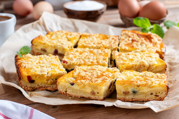 Slice of fresh homemade cottage cheese cake and yeast dough, covered with crumble on a table