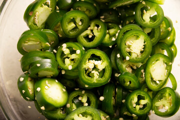 Raw jalapeño chili slices in a glass bowl, a basic ingredient in many dishes and sauces of typical Mexican food.