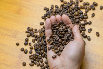 Hands holding roasted coffee beans on a table