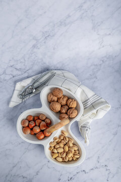 Top view of assorted nuts in a segmented container on marble