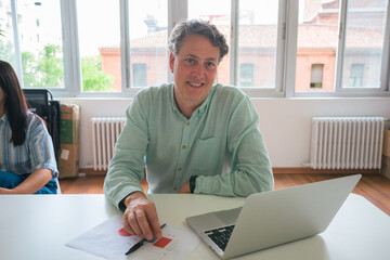 Mature businessman working at a laptop in a bright office