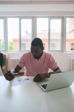 Man analyzing financial reports at a sunlit office desk