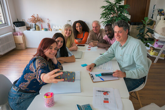 Diverse team in meeting taking selfie in bright office