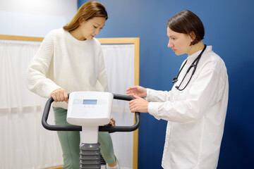 Female doctor cardiologist making bicycle electrocardiogram for examination cardiovascular system...