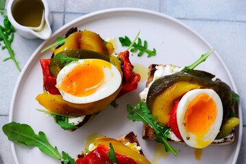 Bruschetta with cream cheese, baked bell peppers, arugula and soft-boiled egg..selective focus