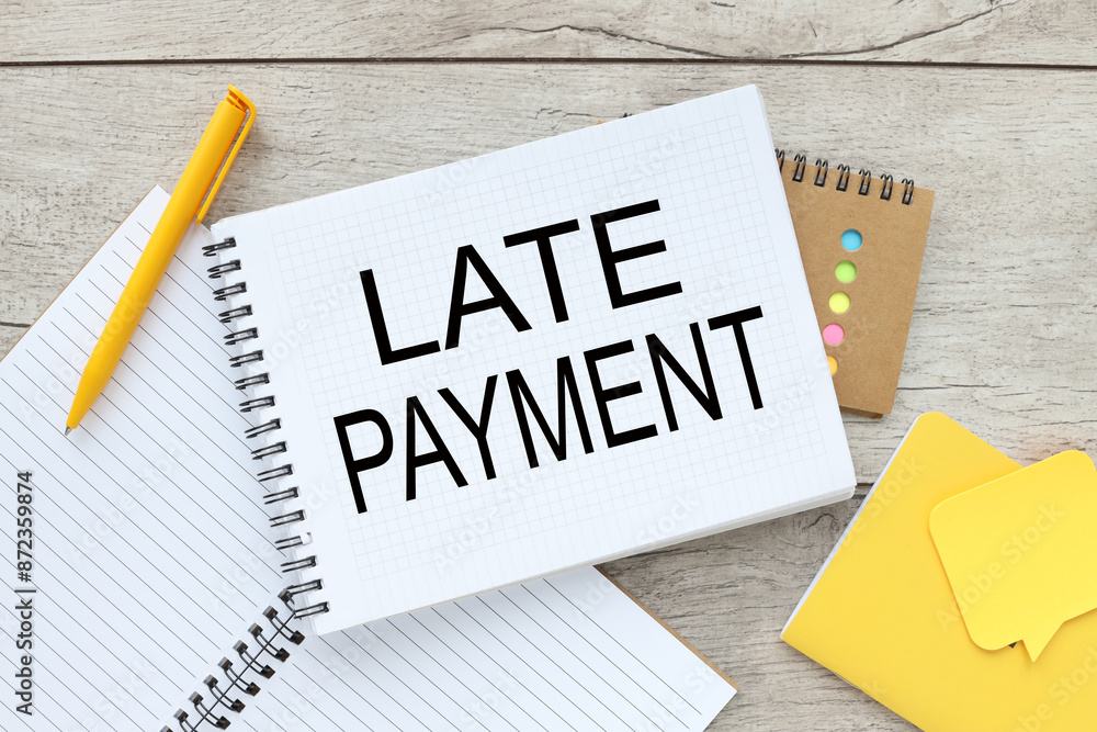 Poster late payment light background text on an open notepad near a yellow pen