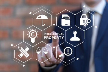Business man working on virtual touch screen presses inscription: INTELLECTUAL PROPERTY....